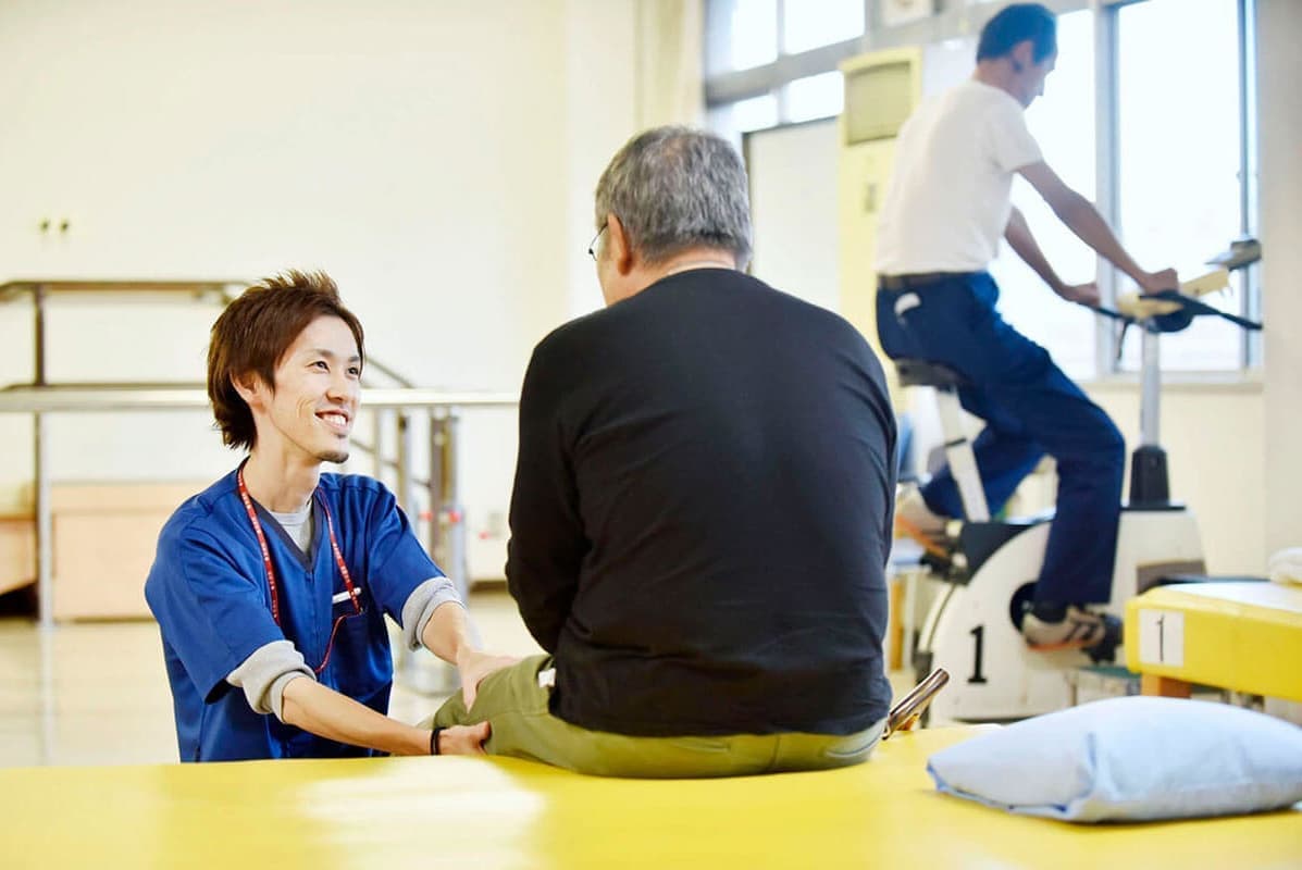 病院で患者に介護をする男性