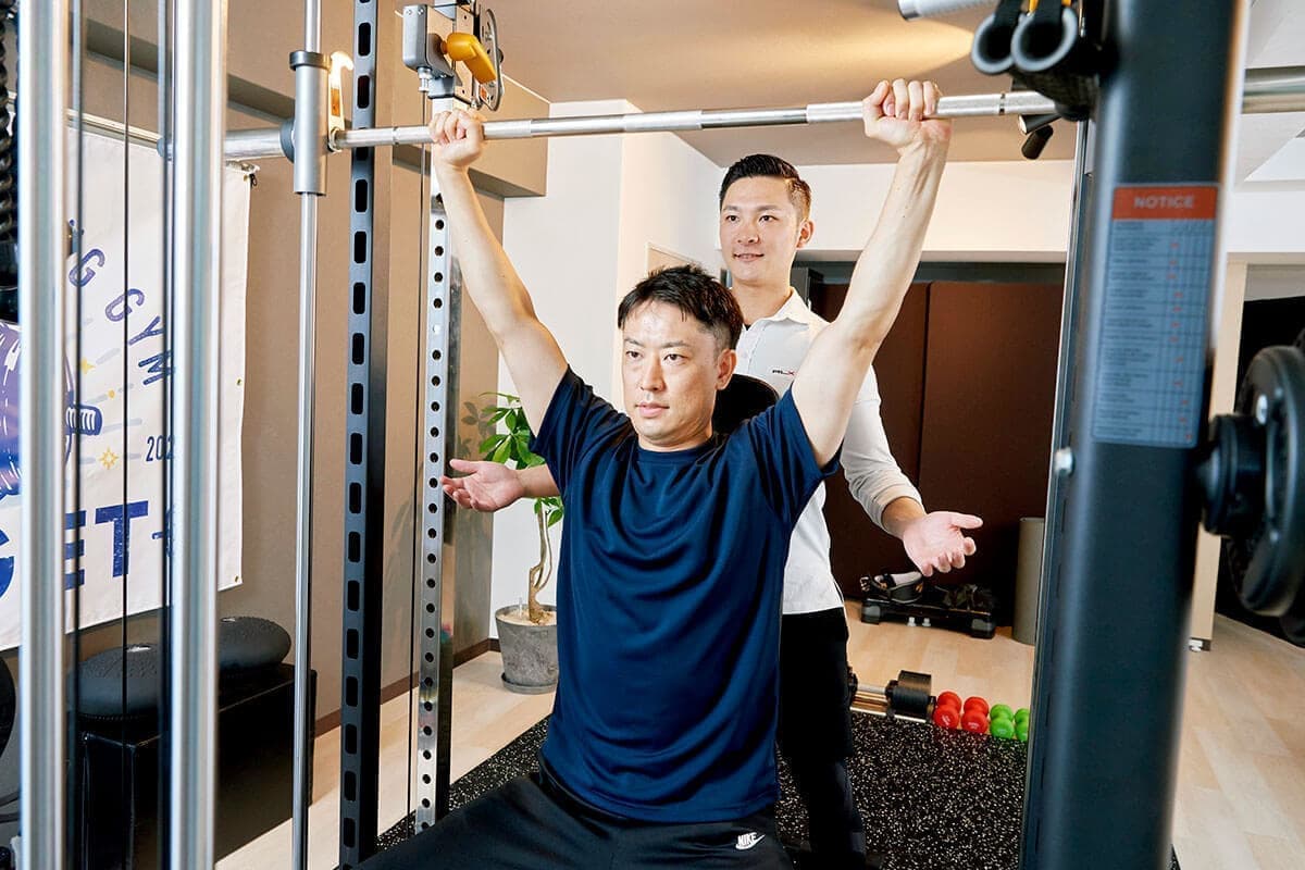 バーベルをあげる男性とトレーナー