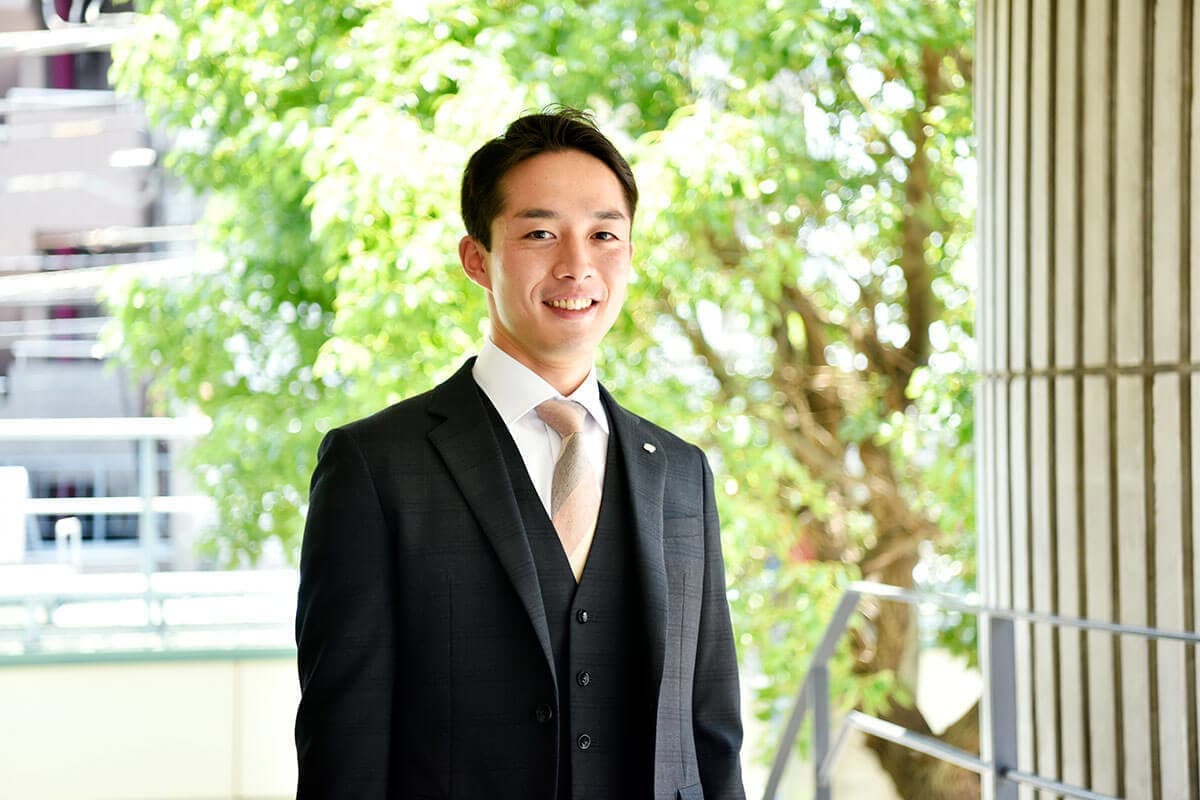 緑の前に立つ男性社員の写真