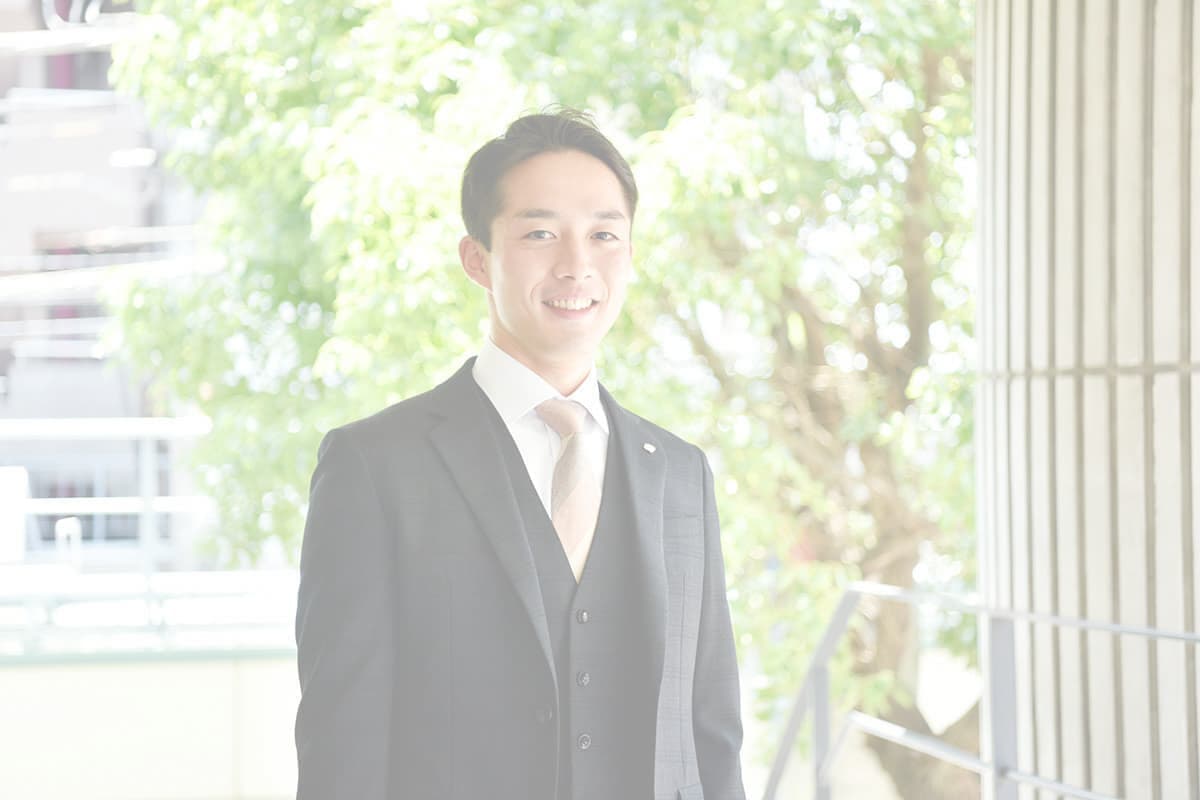 緑の前に立つ男性社員の写真