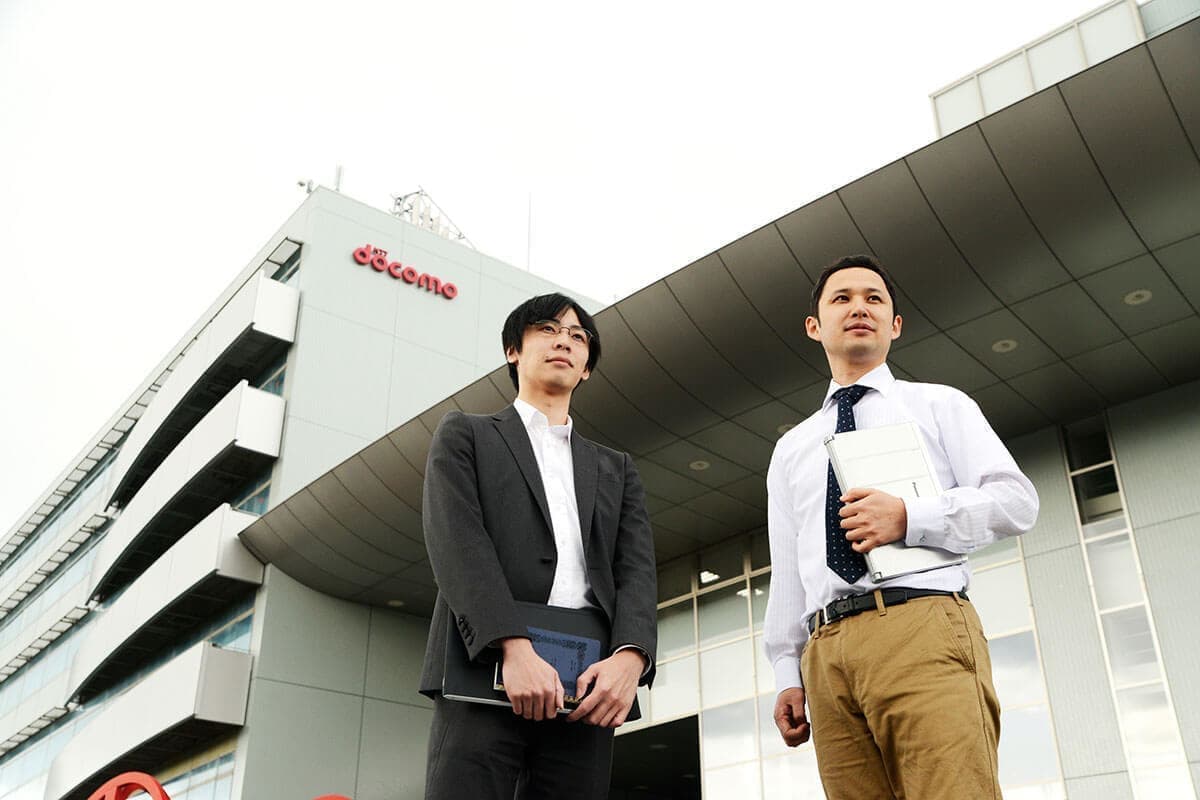会社の前に立つ男性の写真